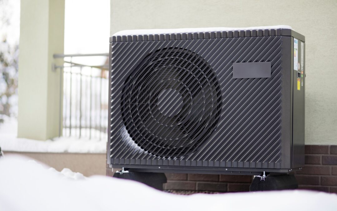 Frost-covered outdoor heat pump unit next to a snow-dusted house in British Columbia, with early morning light
